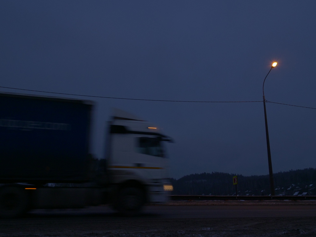 Photo of a semi driving on a highway at dusk.