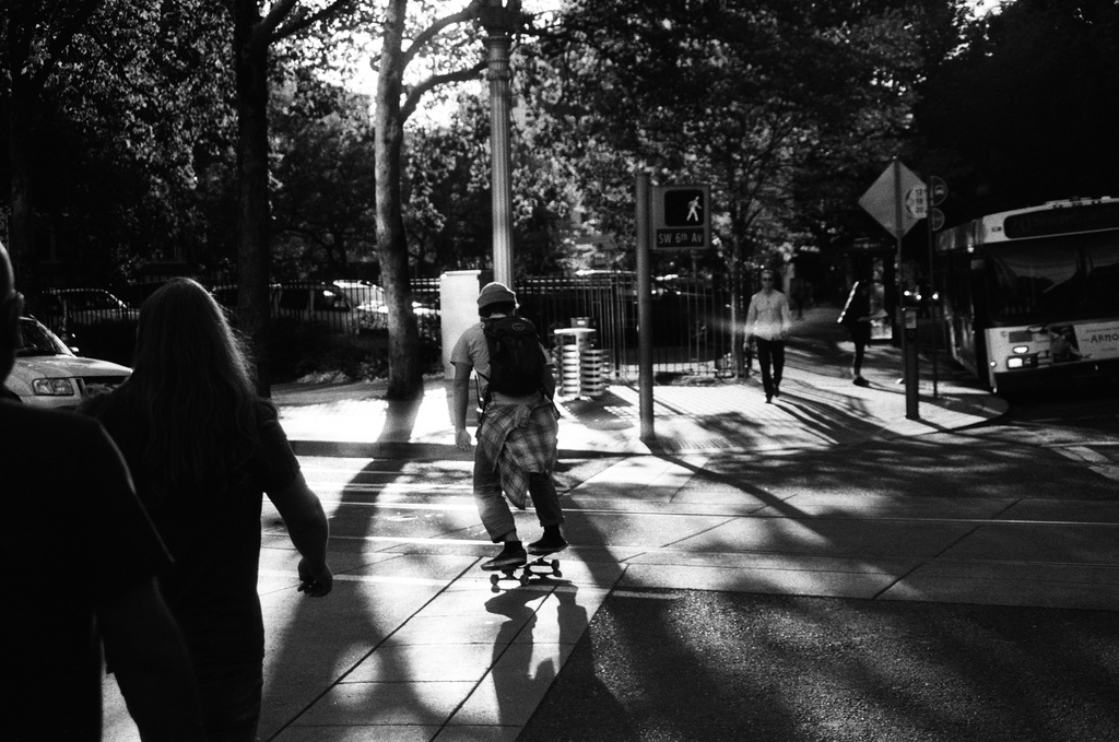 Black and white photo of many skateboarding in a city.