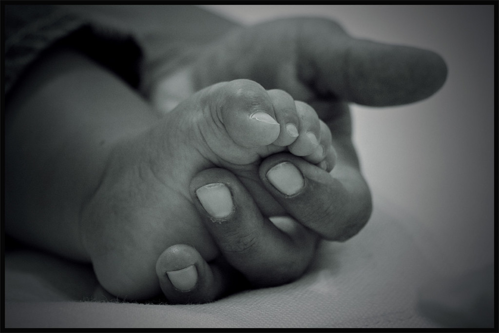 Black and white photo of mother holding baby's foot.