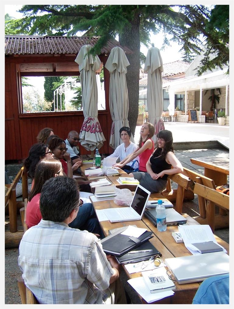 writers sitting around a table outside in greece