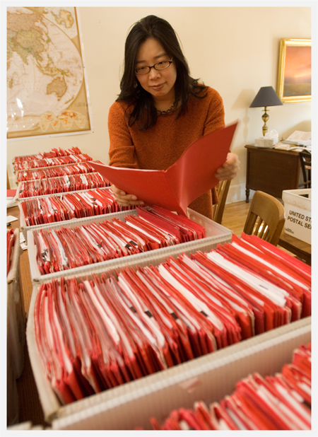 a woman looking at a long line of red file folders