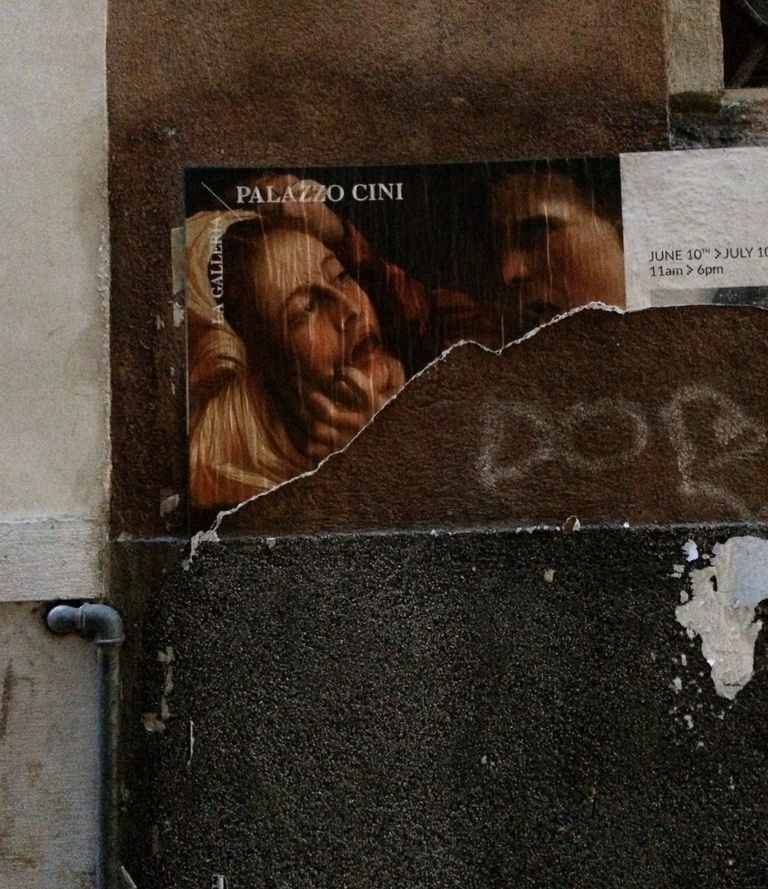 Photo of a side of a building where an advertisement for an art gallery that was pasted onto the building has been ripped off.