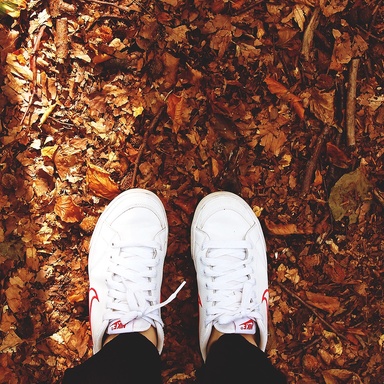 looking down at tennis shoes on fallen leaves