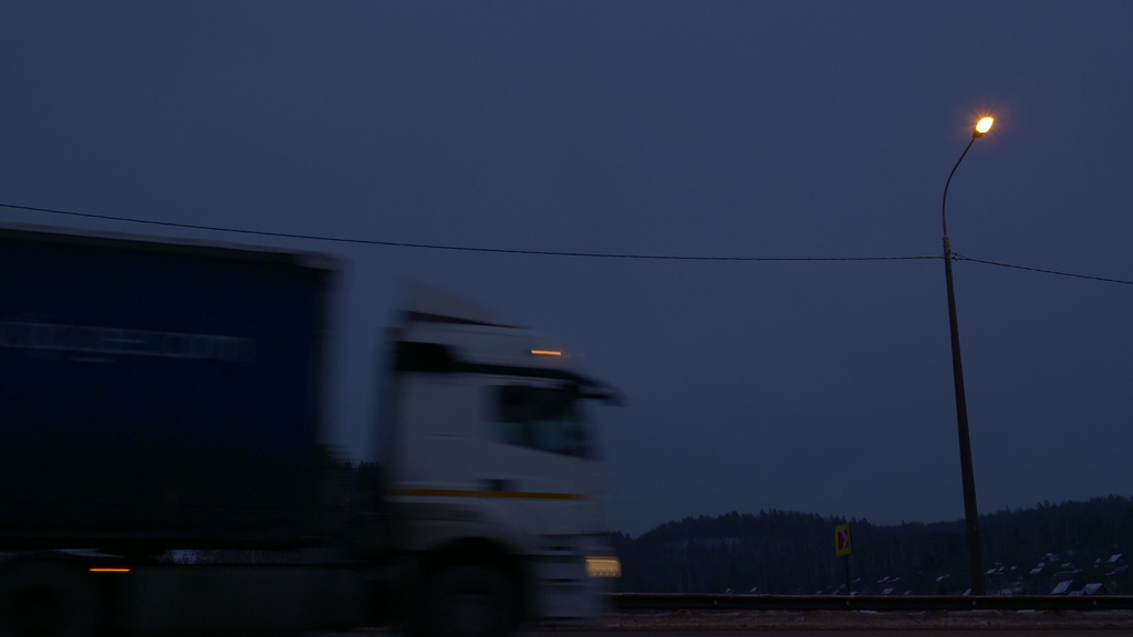 Photo of a semi driving on a highway at dusk.