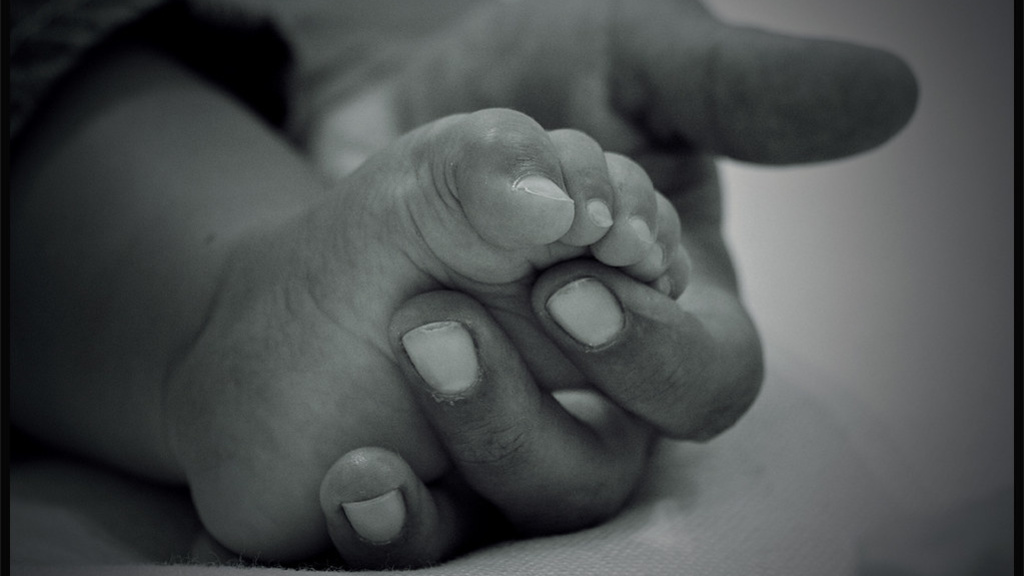 Black and white photo of mother holding baby's foot.